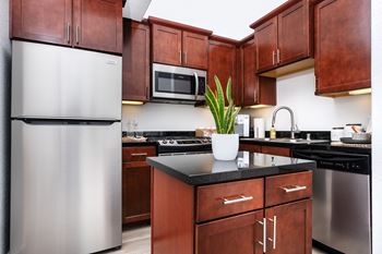 A kitchen with brown cabinets and a stainless steel refrigerator.